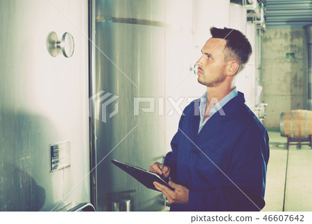 Young man in coat taking notes on wine factory Young man in coat taking notes on wine factory 46607642