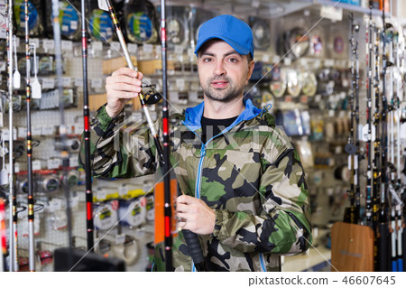 Fisherman customer in fishing clothing choosing fishing rod Fisherman customer in fishing clothing choosing fishing rod 46607645
