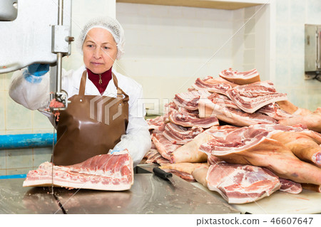 Workwoman cutting meat on band cutting saw Workwoman cutting meat on band cutting saw 46607647