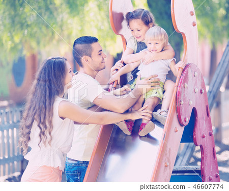 Smiling parents helping kids on slide 46607774