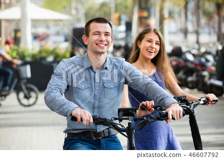 Happy young man and woman with electrkc bikes 46607792