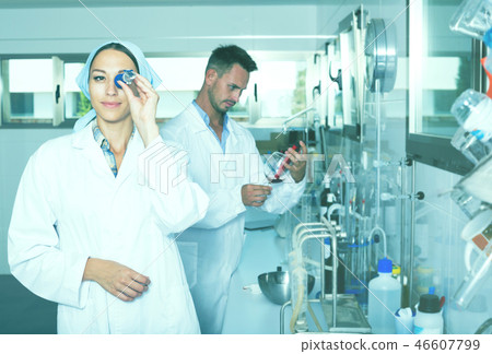 Woman expert in white coat testing wine in chemistry lab 46607799