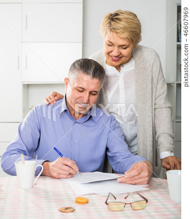 attentive mature couple at table attentively study documents 46607969