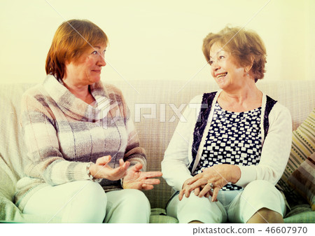Female pensioners discussing something and laughing indoors Female pensioners discussing something and laughing indoors 46607970