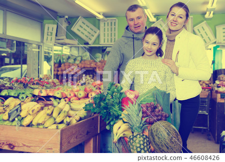 Happy family with smalldaughter standing with full grocery cart Happy family with smalldaughter standing with full grocery cart 46608426