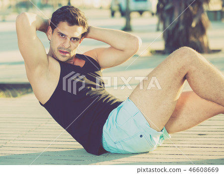 Male athlete doing situps outdoors 46608669