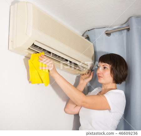 Woman dusting air conditioning Woman dusting air conditioning 46609236