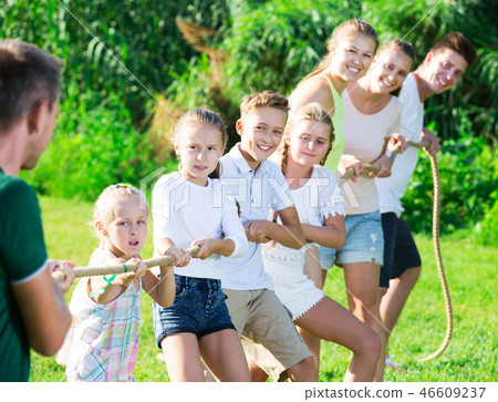 people with kids having fun outdoors pulling rope 46609237