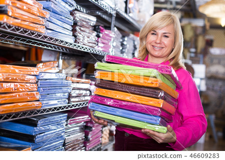 Woman showing stack of bedsheet in the textile shop 46609283