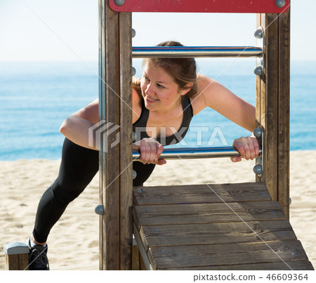 Woman training on fitness station on beach 46609364