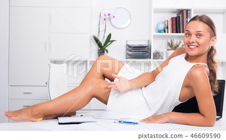 Manager woman sitting on desk with documents Manager woman sitting on desk with documents 46609590