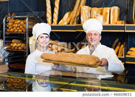 staff offering fresh baguettes and buns in bakery staff offering fresh baguettes and buns in bakery 46609651