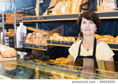 Woman baker with tasty baguettes and other bread products Woman baker with tasty baguettes and other bread products 46609880