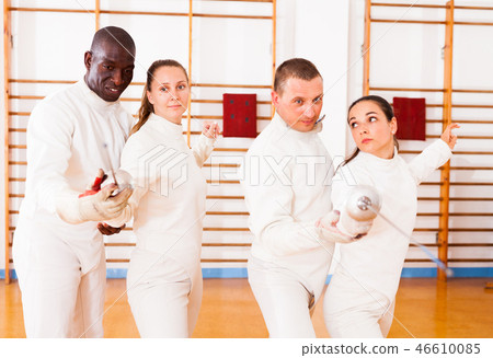Men and women fencers posing with foils together at fencing workout Men and women fencers posing with foils together at fencing workout 46610085