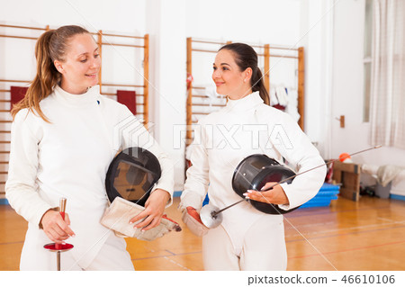 Active young women fencers in uniform talking at fencing room 46610106