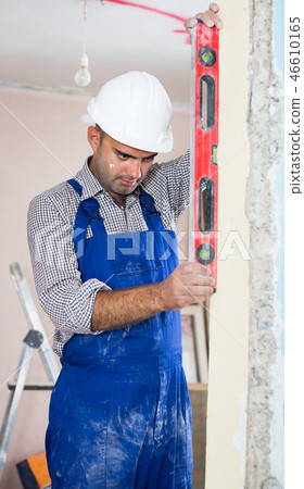 Repairman in helmet is measuring doorway 46610165