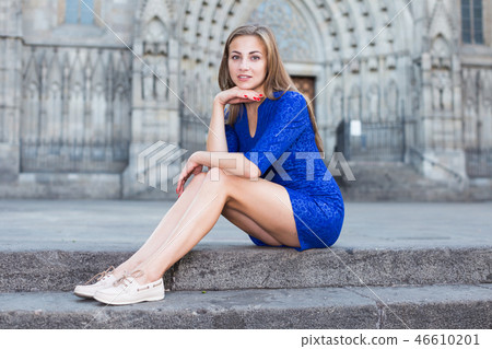Cheerful female is playfully posing sitting in blue dress on the stairs Cheerful female is playfully posing sitting in blue dress on the stairs 46610201