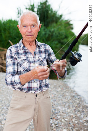 Mature man angling at riverside 46610225