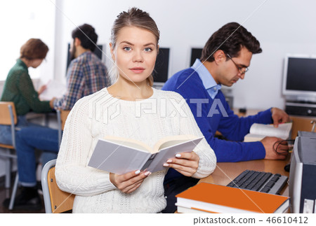 female student reading textbook while studying 46610412