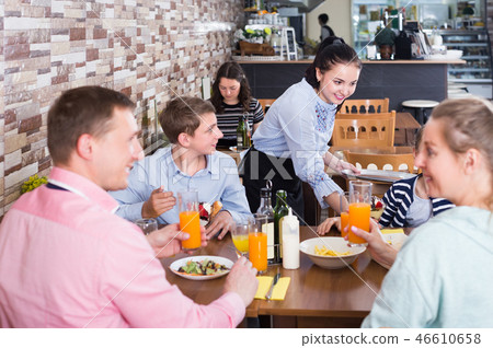 Polite charming waitress serving dishes to family Polite charming waitress serving dishes to family 46610658