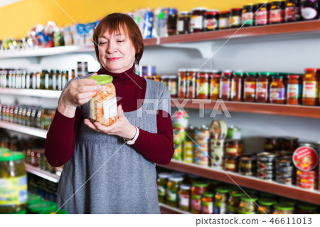 Woman in shop holding preserves 46611013