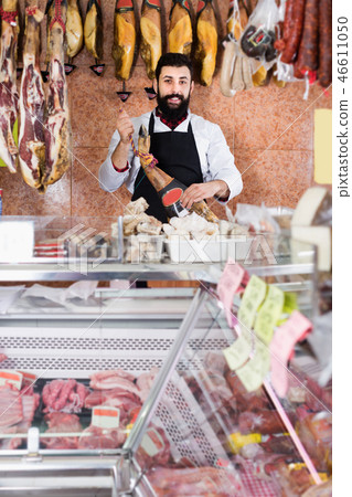 Man shop assistant showing Spanish jamon Man shop assistant showing Spanish jamon 46611050