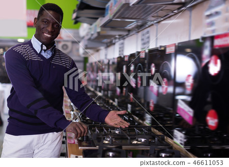 Happy man selecting new cooking top in store 46611053