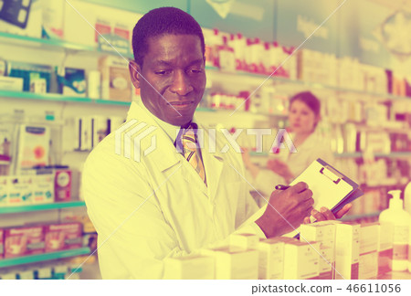 African American man pharmacy chemist making notes on clipboard African American man pharmacy chemist making notes on clipboard 46611056