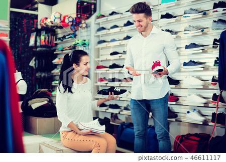 Positive seller demonstrating sneakers to female 46611117