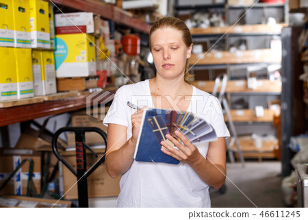 Woman standing near shelves holding notebook and samples in build store Woman standing near shelves holding notebook and samples in build store 46611245