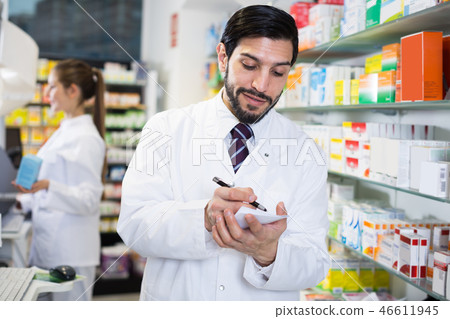 Man pharmacist is inventorying medicines Man pharmacist is inventorying medicines 46611945