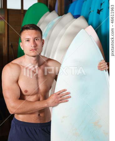 Glad guy surfer posing with surfboard 46611963
