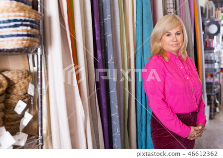 Mature woman standing among shelf in the curtains shop Mature woman standing among shelf in the curtains shop 46612362