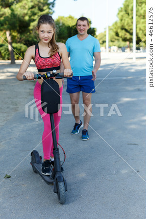 Girl riding kick scooter with father Girl riding kick scooter with father 46612576