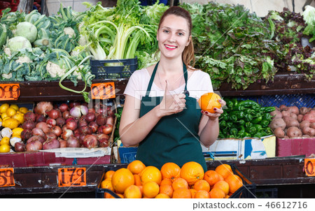 Seller female is holding oranges on her workplace in the market. Seller female is holding oranges on her workplace in the market. 46612716