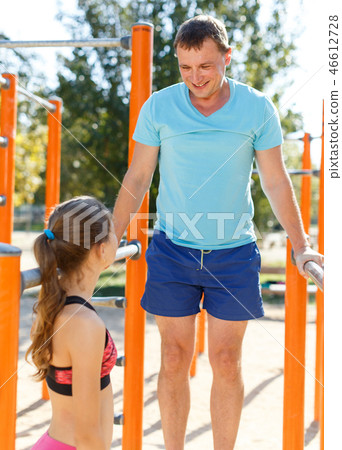 Man showing to daughter exercises on parallel bars 46612728