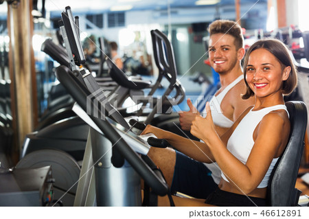 Woman and man using bicycle gym machinery together Woman and man using bicycle gym machinery together 46612891