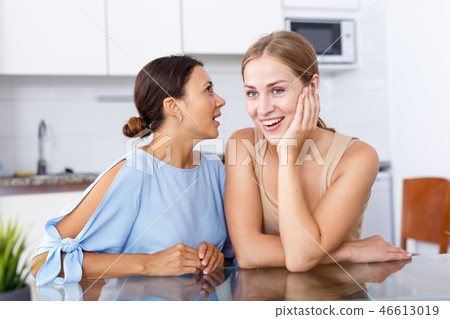 Portrait of young smiling girlfriends sharing secrets and chatting at table Portrait of young smiling girlfriends sharing secrets and chatting at table 46613019