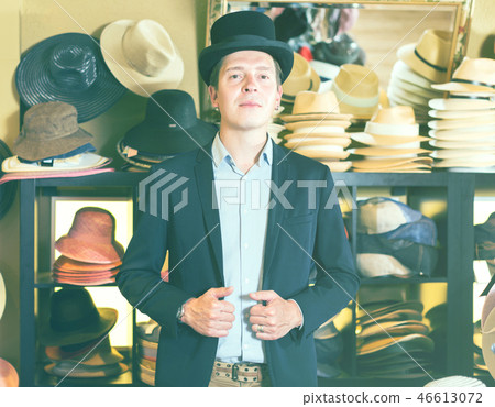 cheerful adult male shopping in botique and try on cylinder hat cheerful adult male shopping in botique and try on cylinder hat 46613072