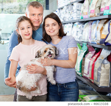 Portrait of friendly family with their puppy during visit of pet shop Portrait of friendly family with their puppy during visit of pet shop 46613108