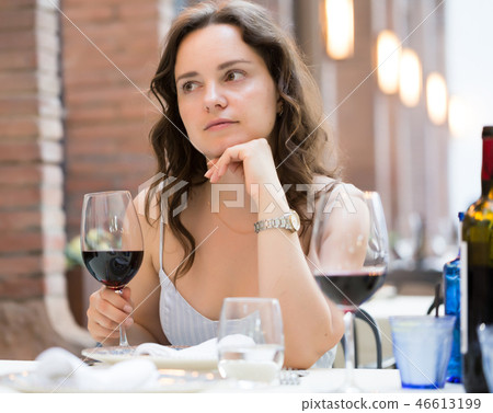 Woman with glass of red wine sitting at outdoor restaurant 46613199