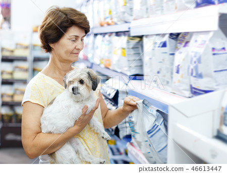 Elderly woman choosing dog food for her puppy Elderly woman choosing dog food for her puppy 46613447