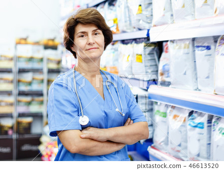 Portrait of confident elderly woman veterinarian standing near shelves with dog food in pet supplies store 46613520