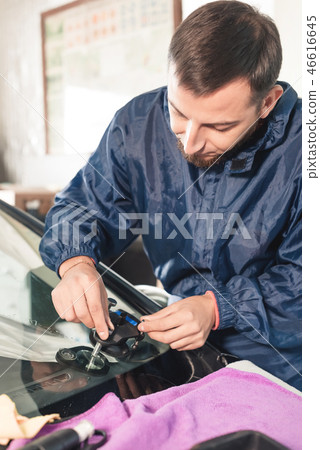 Close-up of a professional windshield repairman working with hydraulic polymer crack filler Close-up of a professional windshield repairman working with hydraulic polymer crack filler 46616645