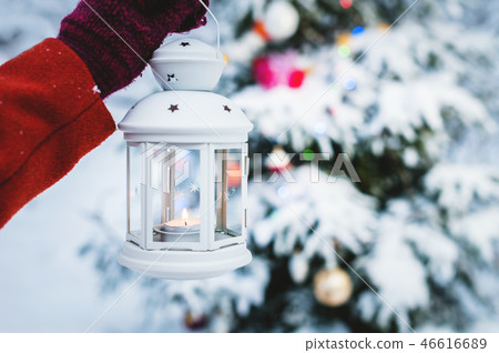 Close-up of a female hand in a mitten with a hand holding a lantern with candles inside against the 46616689