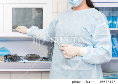 Doctor's hand holding vascular clamps in the operating room. Instruments for surgery in sterile box 46617457