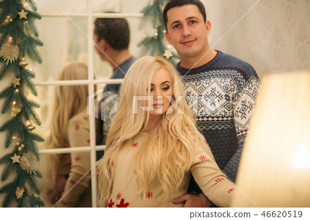 Happy couple stand near the mirror in Christmas time. Holliday spirit 46620519