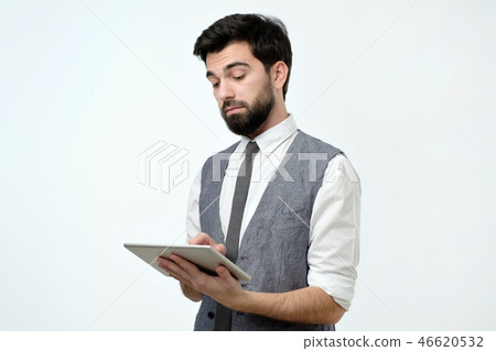 Pensive young handsome man using his digital tablet surfing in internet Pensive young handsome man using his digital tablet surfing in internet 46620532