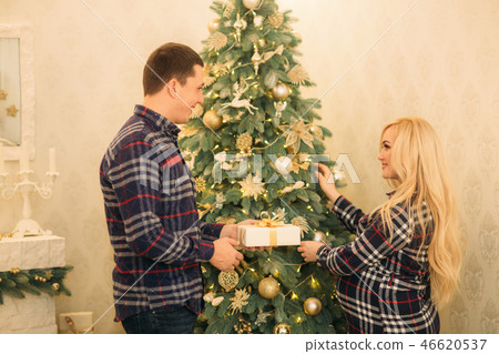 Man gives to his pregnant woman a present. Home. Christmas tree 46620537
