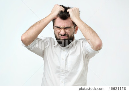 Enraged young businessman pulling his hair out for exasperation, having a burnout at work Enraged young businessman pulling his hair out for exasperation, having a burnout at work 46621158